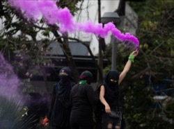 A demonstrator holds a flare during a protest against the violence against the women in Mexico City, Aug. 16, 2020.