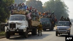 Un véhicule de la police passe à côté des camions transportant des musulmans voyageant pour Bangui, Centrafrique, 17 janvier 2014. 