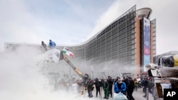 FILE - European dairy farmers spray the EU Council building with milk powder to protest the crisis in their sector, in Brussels, Jan. 23, 2017. 