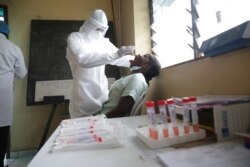 A health worker collects an oral swab from a woman during a COVID-19 coronavirus test at the Nkembo health center in Libreville, Gabon, July 9, 2020.