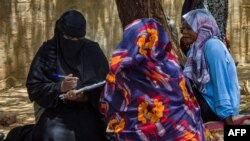 FILE - Women are interviewed under the shade of a tree outside at a camp for the internally displaced in al-Suwar, about 15 kilometres north of Wad Madani, on June 22, 2023.