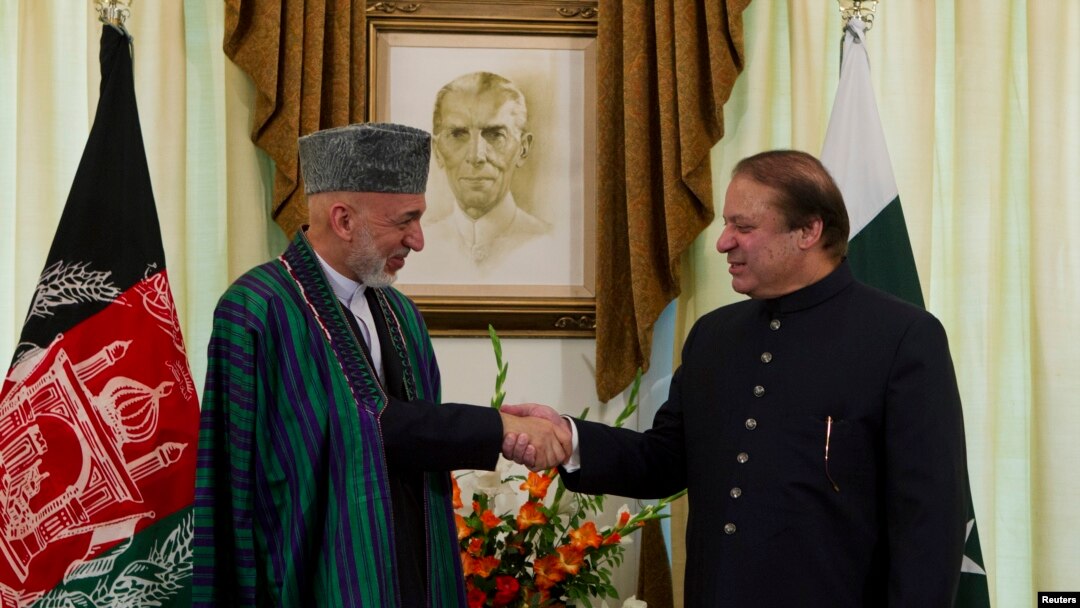 Presiden Afghanistan Hamid Karzai (kanan) berjabat tangan dengan PM Pakistan Nawaz Sharif di kediamannya di Islamabad (26/8).