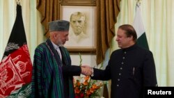 Presiden Afghanistan Hamid Karzai (kanan) berjabat tangan dengan PM Pakistan Nawaz Sharif di kediamannya di Islamabad (26/8).