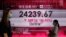 People wearing face masks walk past a bank's electronic board showing the Hong Kong share index at Hong Kong Stock Exchange Sept. 21, 2020. 
