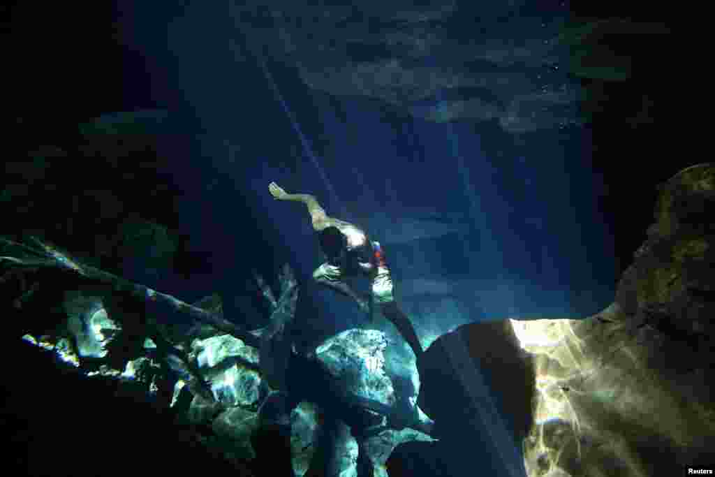 A worker of the cavern of Poco Azul (Blue well) dives to search for belongings dropped by tourists, ahead of World Water Day, in Bahia, Brazil, March 21, 2017.