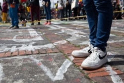 Una manifestante se para sobre los contornos pintados de los cuerpos que representan a los colombianos que desaparecieron durante las protestas anteriores, en Bogotá, el 20 de julio de 2021.