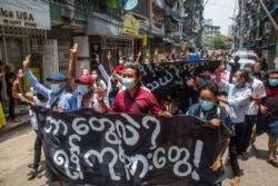Anti-coup protesters hold a banner that reads "What are these? We are Yangon residents!" as they march during a demonstration in Yangon, Myanmar, April 27, 2021.
