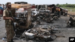 Seorang serdadu Pakistan berjaga sementra para petugas penyelamat di lokasi meneliti TKP dari ledakan truk tanki di jalan raya dekat Bahawalpur, Pakistan, Minggu, 25 Juni 2017 (foto: AP Photo/Iram Asim)