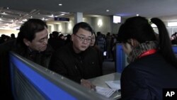 Foreigners speak with sales person about mobile phone service at Pyongyang Airport in Pyongyang, North Korea. (File photo).