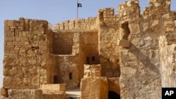 FILE - In this picture released May 22, 2015, by the website of Islamic State militants, shows the Islamic State group's flag, top center, raised on the to top of Palmyra castle, in the Syrian town of Palmyra.