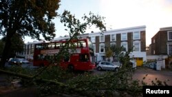 Sebuah bus melewati sebuah pohon yang rubuh di wilayah Islington, London utara, setelah badai St. Jude menghantam wilayah Selatan Inggris (28/10).