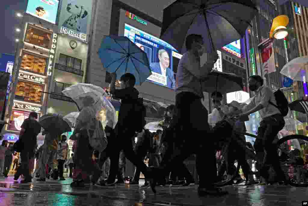 행인들이 붐비는 일본 도쿄 시내의 대형 스크린에 스가 요시히데 총리가 급증하는 신종 코로나바이러스 확산으로 비상 사태를 선포하는 뉴스가 보도되고 있다. 