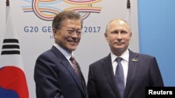 Le président russe Vladimir Poutine et son homologue sud-coréen Moon Jae-In échangent une poignée de main lors d'une rencontre en marge du sommet du G20 à Hambourg, Allemagne, 7 juillet 2017.