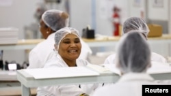 FILE - Women interact at their solar panel factory called Ener-G-Africa, where they produce high-quality solar panels made by an all-female team, in Cape Town, South Africa, Feb. 9, 2023.