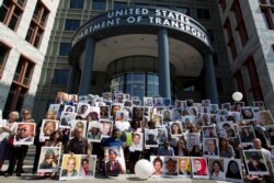 Demonstrators hold pictures of the plane crash victims during a vigil outside the Department of Transportation on the six-month anniversary of the crash of a Boeing 737 Max 8, in Ethiopia, March 10, 2019.
