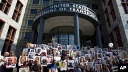 FILE - Demonstrators hold pictures of plane crash victims during a vigil on the six-month anniversary of the crash of a Boeing 737 Max in Ethiopia, which led to the grounding of the planes worldwide, in Washington, Sept. 10, 2019.