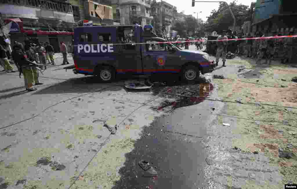 Paramilitary soldiers and police officers gather at the site of a bomb blast in Karachi, Pakistan, June 26, 2013. 