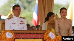 FILE - Thailand's Crown Prince Maha Vajiralongkorn (L) and Royal Consort Princess Srirasmi watch the royal plowing ceremony in Bangkok.