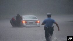 Un policía en Filadelfia intenta socorrer a un automovilista en medio de las inundaciones que causó la toermenta Isaías el 4 de agosto de 2020 en la costa atlántica de EE.UU.