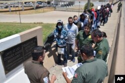 United States Border Patrol officers return a group of migrants back to the Mexico side of the border as Mexican immigration officials check the list, in Nuevo Laredo, Mexico, July 25, 2019.