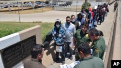 United States Border Patrol officers return a group of migrants back to the Mexico side of the border as Mexican immigration officials check the list, in Nuevo Laredo, Mexico, July 25, 2019.