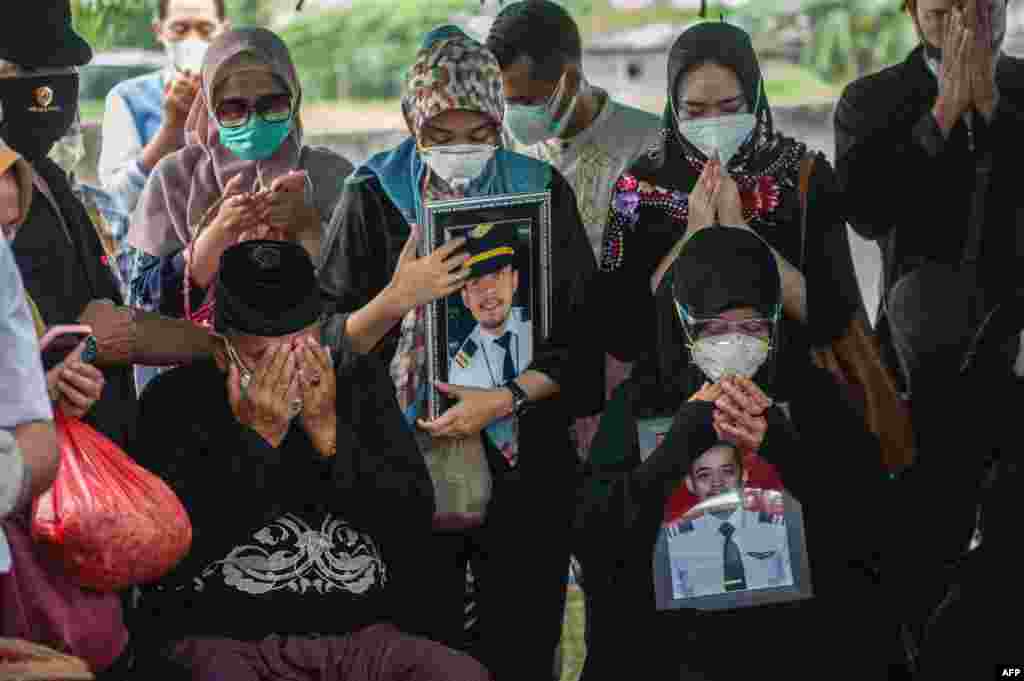 Relatives of Fadly Satrianto, a co-pilot with Nam Air and a passenger onboard Sriwijaya Air flight SJ182 which crashed into the Java sea minutes after takeoff from Jakarta on January 9, pray during his funeral in Surabaya, Indonesia.