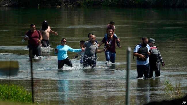 ARCHIVO - Un grupo de migrantes, principalmente de Venezuela, vadea el río Bravo al cruzar la frontera entre Estados Unidos y México el miércoles 16 de junio de 2021 en Del Rio, Texas.