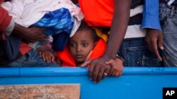 Un garçon est assis dans une embarcation en bois transportant plus de 700 migrants, vers Sabratha, Libye, le 29 août 2016.