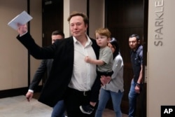 Twitter CEO Elon Musk waves as he leaves carrying his child after speaking at the POSSIBLE marketing conference, Tuesday, April 18, 2023, in Miami Beach, Fla. (AP Photo/Rebecca Blackwell)