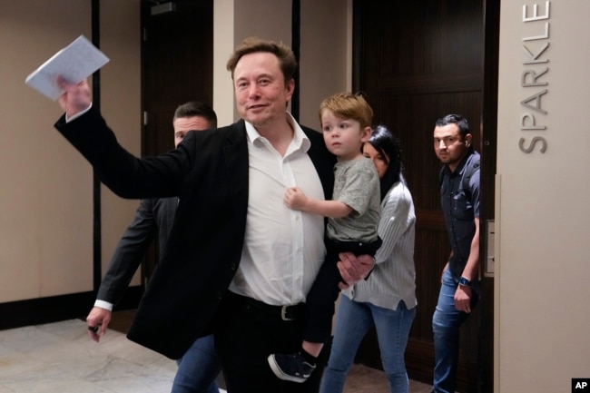 Twitter CEO Elon Musk waves as he leaves carrying his child after speaking at the POSSIBLE marketing conference, Tuesday, April 18, 2023, in Miami Beach, Fla. (AP Photo/Rebecca Blackwell)