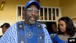 George Weah didampingi istrinta Clar, berbicara kepada media di luar rumahnya di Monrovia, Liberia. 