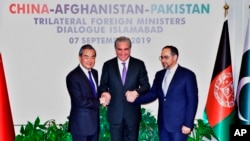 Pakistani Foreign Minister Shah Mahmood Qureshi, center, shakes hands with Afghan counterpart Salahuddin Rabbani, right, and Chinese counterpart Wang Yi in Islamabad, Pakistan, Sept, 7, 2019.