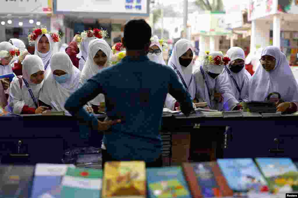 Students check books at a stall during the month-long Amar Ekushey Boi Mela, an annual book fair, at Suhrawardy Udyan, in Dhaka, Bangladesh.