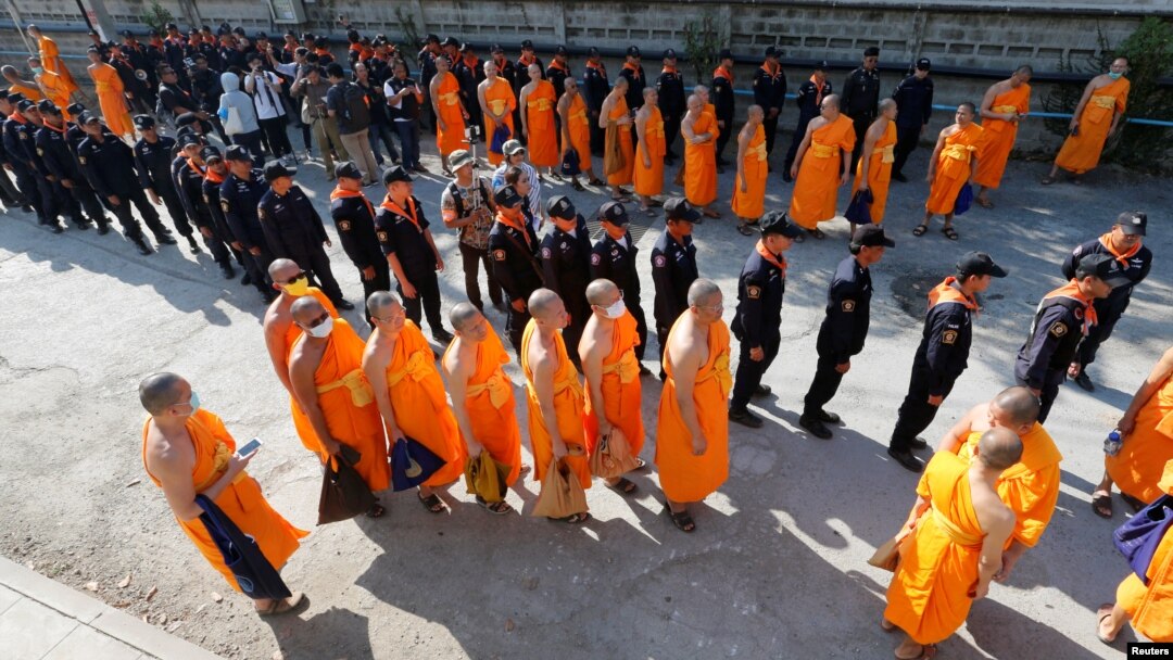 Polisi dan biksu Buddhis berjalan memasuki vihara Dhammakaya untuk mencari biksu Buddhis yang menjadi buron di provinsi Pathum Thani, Thailand (17/2). (foto: REUTERS/Chaiwat Subprasom)