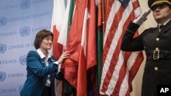 A United Nations police officer salutes as Switzerland's United Nations Ambassador Pascale Baeriswyl, left, as she installs her country's flag during a ceremony for five newly-elected non-permanent members to serve on the United Nations Security Council for the term 2023-2024, Jan. 3, 2023 at U.N. headquarters.