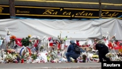 FILE - People mourn in front of the screened-off facade of the Bataclan Cafe adjoining the concert hall, one of the sites of the deadly Nov. 13 Paris attacks that killed 130 people, in Paris, France, Nov. 26, 2015. 