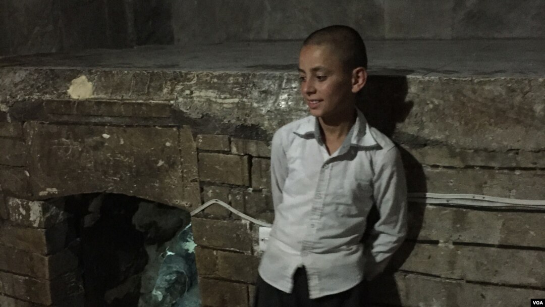 Seorang anak laki-laki Yazidi berdiri di dekat pintu masuk kuil Yazidi di Lalish, Irak.