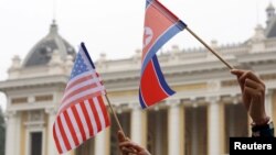 Warga memegang bendera AS dan Korea Utara sambil menunggu iring-iringan mobil pemimpin Korea Utara Kim Jong Un dalam perjalanan ke Hotel Metropole untuk KTT AS-Korea Utara kedua di Hanoi, Vietnam, 28 Februari 2019. (Foto: REUTERS/Kham)