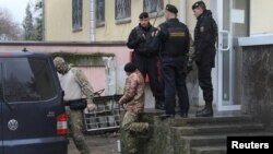 A crew member (C) of one of three Ukrainian naval ships, which were attacked and seized by Russia Sunday, is escorted after a court hearing in Simferopol, in Russia-annexed Crimea, Nov. 27, 2018.