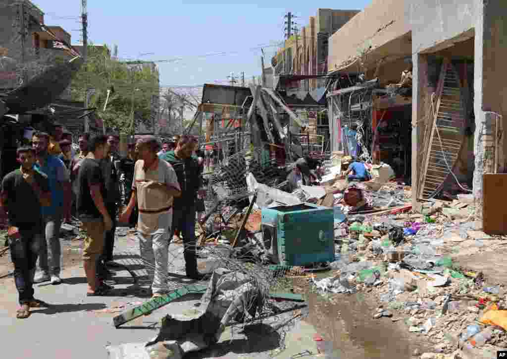 People inspect the site of a car bomb attack in Baghdad, Aug. 13, 2014.