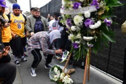 People gather around a makeshift memorial for former NBA and Los Angeles Lakers player Kobe Bryant after learning of his death, at LA Live plaza in front of Staples Center in Los Angeles, California, Jan. 26, 2020.