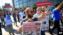 Activists, one holding today's copy of the Cumhuriyet newspaper, march to a court in Istanbul, July 24, 2017, protesting against the trial of journalists and staff from the newspaper, accused of aiding terror organizations. 