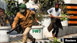 A farmer chases a police officer during a protest against farm laws introduced by the government, in New Delhi, India.