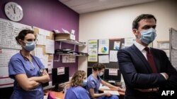 French Health Minister Olivier Veran (R) speaks with medical staff during a visit of the Villefranche-sur-Saone's Nord-Ouest hospital, a few days after it was targeted by cyberattacks, on February 22, 2021. (Photo by JEFF PACHOUD / AFP)