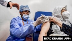 A medical worker administers a dose of Russia's Sputnik V vaccine for COVID-19 disease to a woman at a clinic in the city of Blida, about 45 kilometres southwest of the Algerian capital, on January 30, 2021, (Photo by RYAD KRAMDI / AFP)