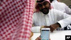 A man reads Aramco's twitter page at a coffee shop in Jiddah, Saudi Arabia, Nov. 3, 2019. Saudi Arabia formally started its initial public offering of its state-run oil giant Sunday.