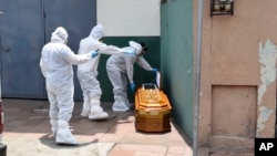 Agents de santé retirant un cercueil avec un corps laissé à l'extérieur d'une maison à Guayaquil pendant la pandémie de Covid-19, Équateur, 6 avril 2020. (Photo AP/Edison Choco)