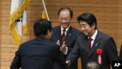 Hwang Woo-yea (tengah), ketua partai berkuasa di Korea Selatan, Saenuri dan kepala parlemen Korea Selatan, bertepuk tangan saat PM Jepang Shinzo Abe (kanan) berjabat tangan dengan seorang anggota parlemen Korea Selatan seusai memberikan sambutan dalam pembukaan sidang parlemen ke-36 parlemen Jepang-Korea Selatan di Tokyo, Jumat (29/11).