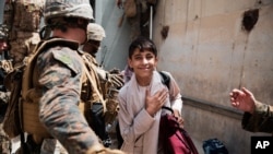In this photo provided by the U.S. Marine Corps, a boy is processed through an Evacuee Control Checkpoint during an evacuation at Hamid Karzai International Airport, in Kabul, Afghanistan, Aug. 18, 2021.