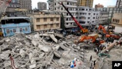 Regu penyelamat menggunakan mesin penggali untuk memindahkan reruntuhan gedung dari bangunan yang ambruk di pusat kota  Dar es Salaam, Tanzania (29/3).